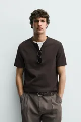 Camiseta de manga corta con cuello panadero y cierre frontal de tres botones. Presenta una textura acanalada y un corte regular fit.