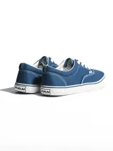 Championes de lona color azul grisáceo, estilo skate o casual, con cordones blancos y suela de goma blanca con una línea fina azul en el borde.