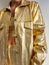 Camisa dorada brillante con cuello clásico, cierre frontal con botones y bolsillos de parche en el pecho.