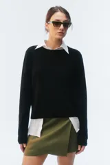 Sweater de tejido de punto verde, con calce regular levemente suelto, escote redondo y mangas largas con puños acanalados.