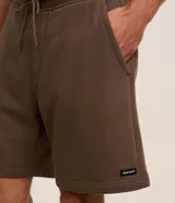 Bermuda masculina de corte slim, confeccionada en tejido de algodón con felpa. Presenta cintura elástica con cordón ajustable, bolsillos laterales y una pequeña etiqueta aplicada en el ruedo.