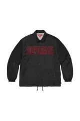 Campera tipo coach de Supreme, color negro, con cierre frontal de botones a presión, cuello clásico y logo bordado en color rojo en el pecho. Cuenta con puños elásticos y cordón ajustable en el ruedo.