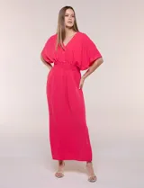 Vestido largo amarillo de corte fluido con escote en V, mangas cortas amplias y apliques de tachas en el escote y puños. Posee cintura elastizada fruncida y falda larga con tajos laterales en el ruedo.