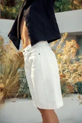 Bermuda de denim color marrón oscuro, de tiro medio y diseño relaxed fit, con cinco bolsillos, trabillas para cinto, bajo desflecado y cierre frontal con cremallera y botón.