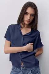 Camisa negra de manga corta, con cuello mao y cierre frontal de botones, de silueta amplia y tejido liviano con textura sutil.