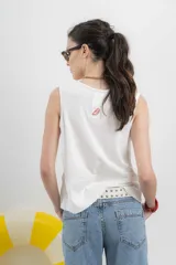 Musculosa blanca de algodón orgánico con escote en U, cortes irregulares y mezcla de texturas. Tiene un fit holgado y cinta aplicada en la espalda con bordado frutal.