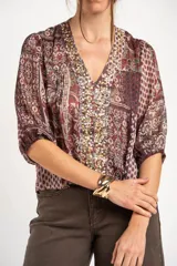 Blusa de manga corta con estampado estilo paisley en tonos burdeos, verde y crudo, escote en V con apliques de lentejuelas doradas y diseño holgado.