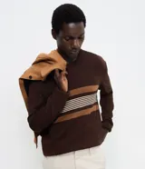 Suéter de punto Marfinno con cuello redondo y mangas largas. Presenta un diseño de rayas horizontales en tonos marrones y beige sobre una base de color marrón oscuro.