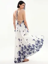 Vestido largo blanco con estampado floral azul, escote halter y corte acampanado.