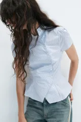 Camisa de manga corta con estampado de rayas verticales en tonos celeste y blanco, cuello alto y cierre frontal cruzado con botones.
