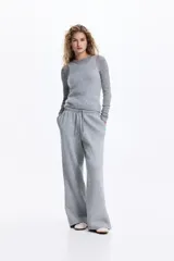 Pantalón de jogging de corte holgado y piernas amplias, confeccionado en felpa con interior cepillado. Presenta cintura elástica con cordón de ajuste y bolsillos laterales discretos.