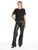 Blusa negra de crepe con cuello redondo y mangas cortas. Presenta terminaciones onduladas en mangas y ruedo, decoradas con una cinta de strass brillante. Cuenta con cierre invisible en la espalda.