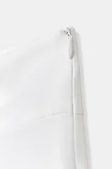 Falda pantalón blanca de tiro bajo con detalle de pliegues en el delantero y dos botones metálicos dorados decorativos en la cintura.