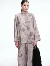 Camisa oversize de lyocell con estampado orgánico efecto lavado. Presenta cuello clásico, cierre frontal con botones, mangas amplias con puños anchos y un diseño de corte relajado con ruedo asimétrico, siendo más largo en la parte posterior.