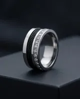 Anillo de acero plateado con banda central negra texturizada, detalles de números romanos y una hilera de circonias.