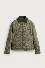 Cazadora acolchada de corte relaxed fit, confeccionada en tejido jacquard con estampado abstracto en tonos verde militar. Cuenta con cuello de solapa en pana verde oscuro contrastante, cierre frontal con cremallera, mangas largas con puños abotonados y amplios bolsillos frontales de plastrón.
