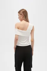Top blanco de poliéster, al cuerpo, con bretel ancho y cuello asimétrico.