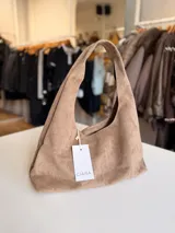 Cartera tipo hobo de diseño flexible y caída natural, confeccionada en material con textura simil gamuza. Cuenta con asa corta integrada para llevar al hombro, cierre superior y bolsillo interior con cierre.