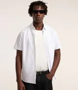 Camisa blanca con rayas celestes, de corte clásico, manga corta y cuello solapa. Confeccionada en fibra de bambú y poliéster.