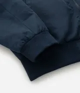 Campera bomber negra para hombre, confeccionada en poliéster con cierre frontal de cremallera, cuello, puños y dobladillo elásticos acanalados, y bolsillos laterales.