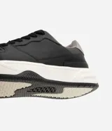 Championes urbanos estilo skate de color negro con suela bicolor blanca y negra, talón gris y detalles perforados en la puntera.