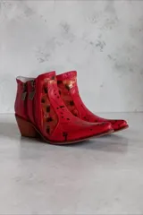 Bota corta de cuero rojo con diseño pintado a mano, inserciones laterales de cuero nonato dorado y negro, taco cuadrado de madera y doble cierre lateral con tiradores metálicos personalizados.