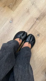 Ballerinas de cuero color negro, inspiradas en el diseño japonés Tabi con punta dividida y lazo decorativo en el empeine.