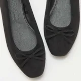 Bailarinas de mujer en color negro, confeccionadas en material tipo antelina con acabado suave. Presentan un diseño clásico de punta redondeada y un pequeño lazo decorativo en la parte frontal.