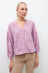 Blusa blanca de manga larga con escote en V y bordados en el frente.