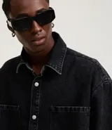Camisa masculina de jeans negro con lavado marmolado, corte boxy, cuello inglés, manga corta, abotonada al frente y con dos bolsillos de parche en el pecho.