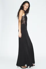 Vestido largo negro de cuello halter con detalles de encaje en la parte superior y espalda. Cuenta con corte en línea evasé y cierre posterior con abertura y botón.