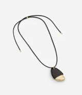 Collar largo con cordón negro y colgante de forma orgánica, mitad negro y mitad dorado. El colgante está hecho de poliuretano, zinc y hierro.