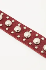 Pulsera de cuero negro con textura grabada, decorada con múltiples tachas metálicas plateadas de diferentes tamaños y cierre con broches a presión.