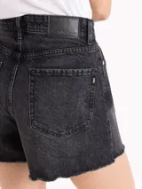 Short de denim negro de tiro medio-alto y silueta relajada, con lavado ácido, sutiles desgastes y terminación de ruedo deshilachado al corte.