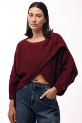 Sweater de punto con diseño cruzado frontal, de silueta amplia y mangas largas con puños ajustados. Presenta un corte holgado y textura suave.