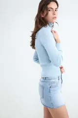 Sweater de punto celeste con diseño acanalado, cuello alto y cierre frontal con doble cremallera metálica, de manga larga y calce al cuerpo.