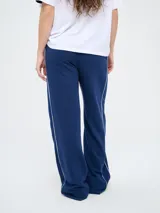 Pantalón de jogging azul marino con cordón ajustable en la cintura, bolsillos laterales y líneas blancas laterales. Presenta el escudo del Club Nacional de Football y el logo de Umbro bordados.