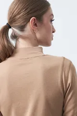 Polera de algodón color blanco, con cuello alto y mangas tres cuartos. Presenta un diseño ajustado al cuerpo con costuras decorativas en las sisas.