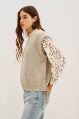 Chaleco de punto color beige, con cuello redondo y volados.