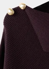 Jersey de punto color marrón oscuro, con diseño recto, cuello asimétrico y manga larga. Presenta detalle de botones efecto joya en el hombro.