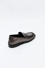 Mocasín de cuero sintético negro con punta cuadrada, detalle de costuras visibles en la capellada y taco bajo.