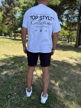 Remera blanca oversize con estampado tipográfico negro en la espalda que incluye texto y un gráfico de un globo terráqueo.
