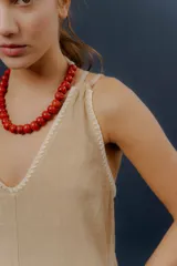 Mono largo de lino color amarillo, con escote en V, tirantes finos y detalles de costuras decorativas blancas en el escote y en los bajos de las piernas anchas.