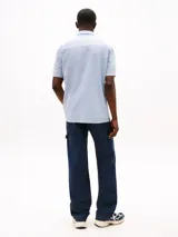 Camisa Tommy Jeans de corte regular, confeccionada en algodón mil rayas con textura. Diseño a rayas verticales celestes y blancas, con cuello abotonado, manga corta y bolsillo de parche en el pecho con logo de la marca.