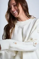 Sweater color crema de hilado frizado con cuello redondo y apliques de flores color beige en las mangas.