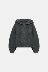 Chaqueta de punto con capucha, manga larga y cierre frontal con cremallera metálica. Presenta un diseño de tejido texturizado en color gris oscuro con detalles en contraste en los puños.