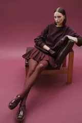 Zapato tipo guillermina de cuero charol color marrón oscuro, con tira T y hebilla ajustable en el lateral. Posee puntera cuadrada y suela de goma color caramelo con taco bajo.