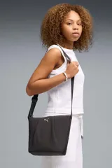 Cartera bandolera Puma tipo bucket bag, de color negro con diseño fruncido, correa ajustable y logo de la marca impreso en dorado en el frente.