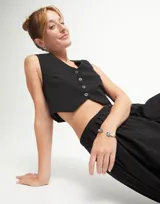 Pulsera rígida de aleación de metales bañada en plata de ley, con dos cristales facetados verdes en forma triangular en los extremos.