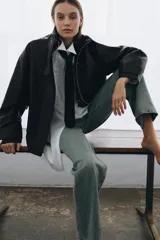 Chaqueta de corte oversize con acabado efecto piel. Presenta cuello alto, cierre frontal con cremallera y botones ocultos bajo solapa, bolsillos de plastrón con solapa en el delantero, mangas largas ajustables con trabillas y bajo ajustable con hebillas metálicas.